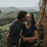 Imagem de um casal se beijando numa plantação de café